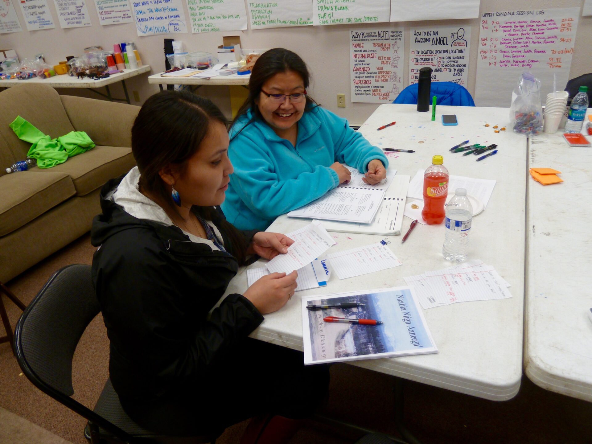 Two women at table reviewing Native language learning documents